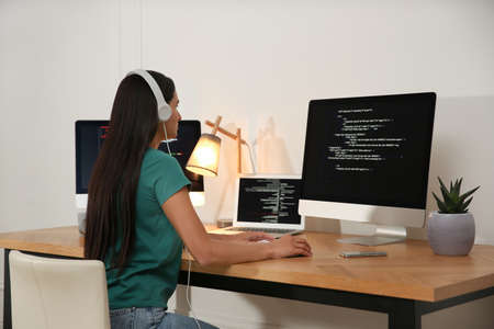 Programmer with headphones working at desk in officeの写真素材
