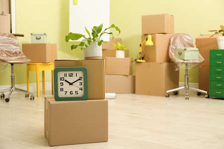 Clock and plant on cardboard boxes in new office, space for text. Moving dayの写真素材