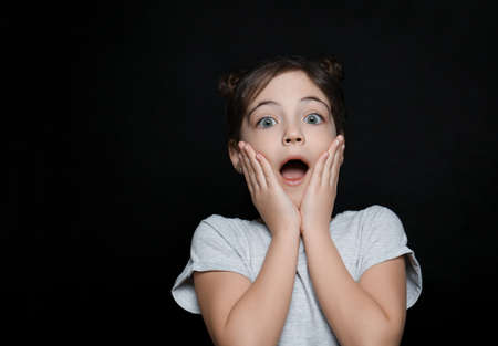 Little girl feeling fear on black backgroundの写真素材