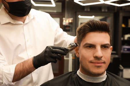 Professional hairdresser making stylish haircut in salon, closeup
