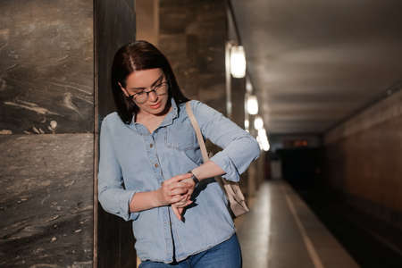 Beautiful woman with backpack looking at wristwatch on subway station. Public transportの写真素材