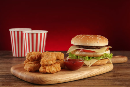Delicious fast food menu on wooden table against red backgroundの写真素材
