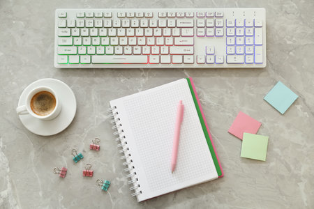Modern keyboard with RGB lighting and stationery on gray table, flat layの写真素材