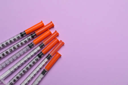 Disposable syringes on violet background, flat lay. Space for textの写真素材