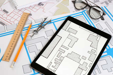 Office stationery, tablet and eyeglasses on cadastral maps of territory with buildingsの写真素材