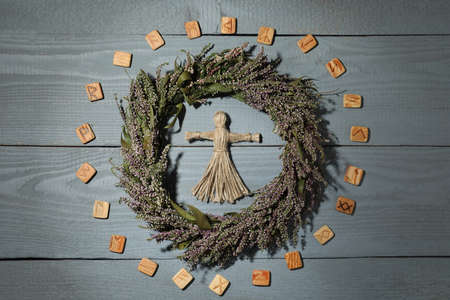 Female voodoo doll, wreath and runes on gray wooden background, flat layの写真素材