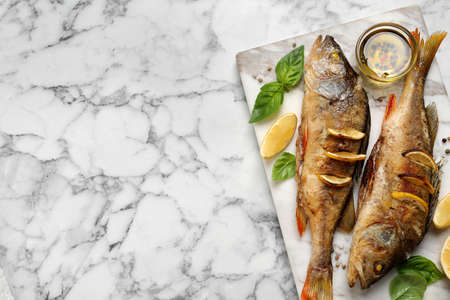 Tasty homemade roasted perches served on white marble table, top view and space for text. River fishの写真素材