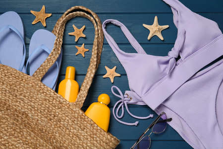 Flat lay composition with beach accessories on blue wooden background