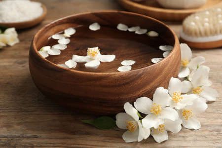 Bowl with water and beautiful jasmine flowers on wooden tableの写真素材