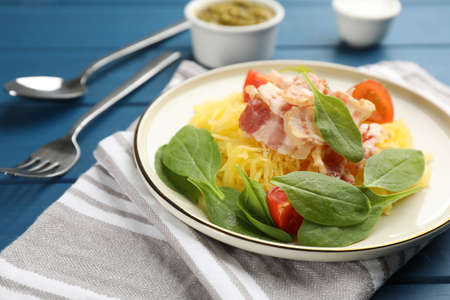 Tasty spaghetti squash with bacon and basil served on blue wooden table, closeup