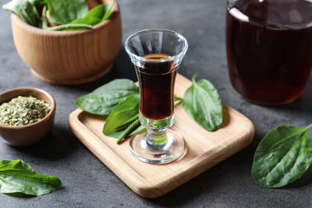Glass of broadleaf plantain tincture on gray tableの写真素材