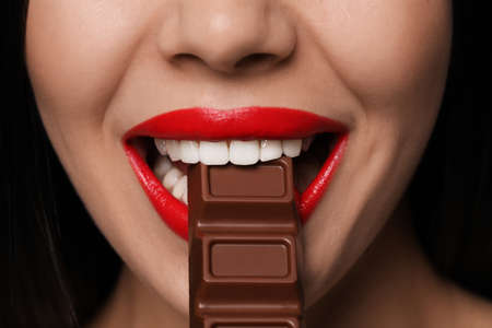 Young woman with red lips eating chocolate, closeupの写真素材