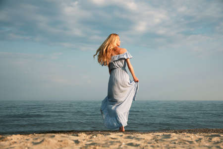 Beautiful young woman on sea beach, back viewの写真素材