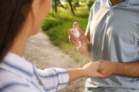 Man applying insect repellent on his girlfriend's arm in park, closeup. Tick bites preventionの写真素材