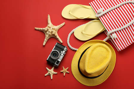 Stylish bag with beach accessories on red background, flat layの写真素材