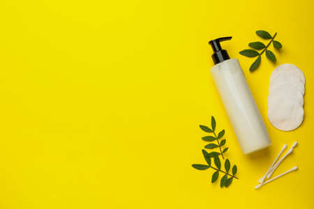 Cotton pads, swabs and makeup removal product on yellow background, flat lay. Space for text