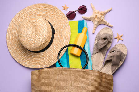 Stylish bag with beach accessories on violet background, flat layの写真素材