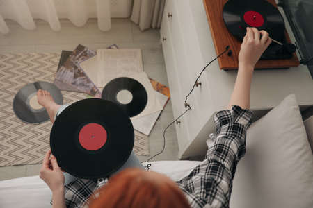 Young woman listening to music with turntable in bedroom, above viewの写真素材