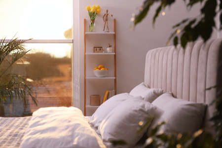 Stylish bedroom interior with wooden ladder near white wall