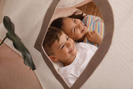 Cute little children lying in toy wigwam at homeの写真素材