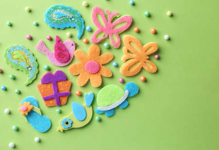 Different small colorful felt items and beads on green background, flat layの写真素材