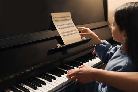Young woman with child playing piano, closeup. Music lessonの写真素材