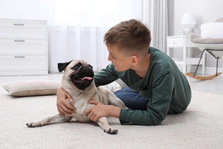 Boy with his cute pug on floor at homeの写真素材