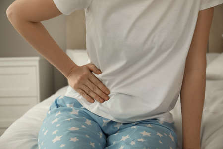 Woman suffering from appendicitis inflammation on bed at home, closeupの写真素材