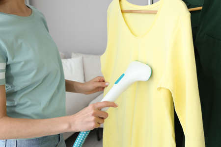 Woman steaming yellow shirt at home, closeupの写真素材