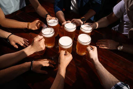 Friends clinking glasses with beer at table, closeupの写真素材