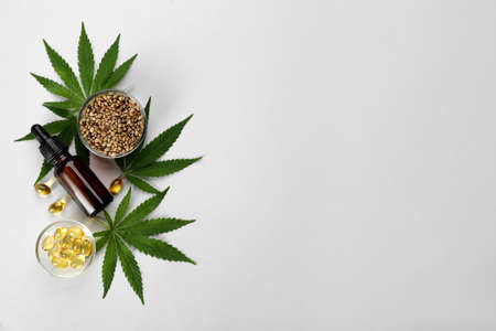 Flat lay composition with CBD oil or THC tincture and hemp leaves on light background, space for textの写真素材