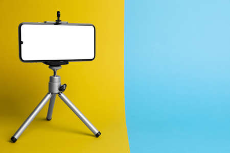 Modern tripod with smartphone on color background. Space for textの写真素材