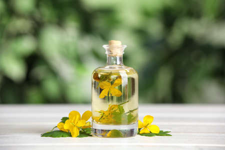 Bottle of celandine tincture and plant on wooden table outdoorsの写真素材