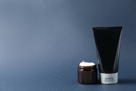Tube and jar of men's facial cream on gray background. Space for textの写真素材