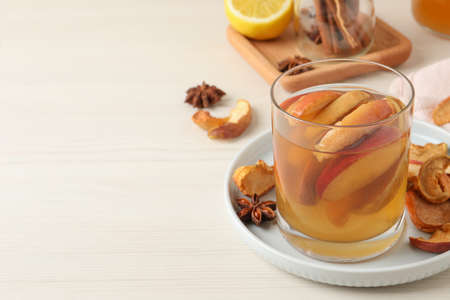 Delicious compot with dried apple slices on light wooden table. Space for text