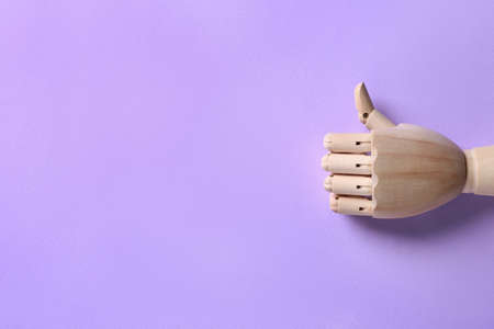 Wooden mannequin hand showing thumb up on lilac background, top view. Space for textの写真素材
