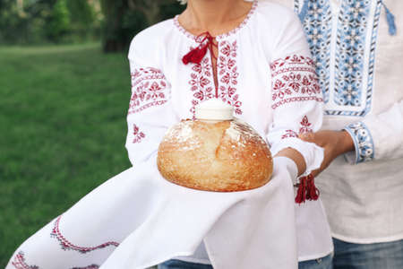Mature couple in national clothes with bread and salt outdoors, closeup. Ukrainian welcoming traditionの写真素材