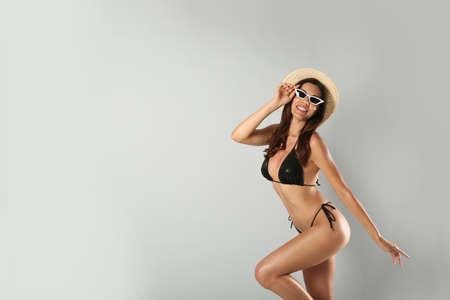 Beautiful woman in stylish bikini, sunglasses and hat on light gray background. Space for textの写真素材