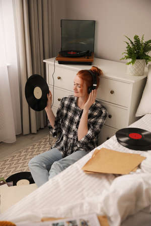 Young woman listening to music with turntable in bedroomの写真素材