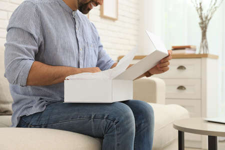 Man unpacking parcel at home, closeup. Online shoppingの写真素材