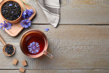 Flat lay composition with tea and cornflowers on wooden table. Space for textの写真素材