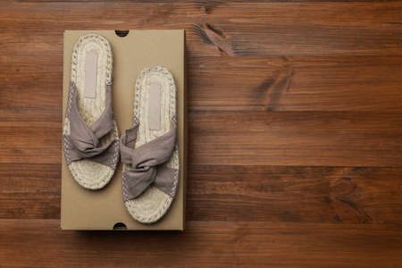Pair of stylish shoes and cardboard box on wooden background, top view. Space for text