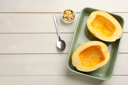 Halves of fresh spaghetti squash in baking dish on white wooden table, flat lay with space for text. Cooking at homeの写真素材