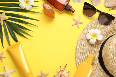 Sun protection products and beach accessories on yellow background, flat lay. Space for text