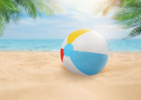 Colorful beach ball on sandy coast near sea