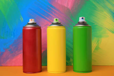 Cans of different spray paints on color background. Graffiti suppliesの写真素材