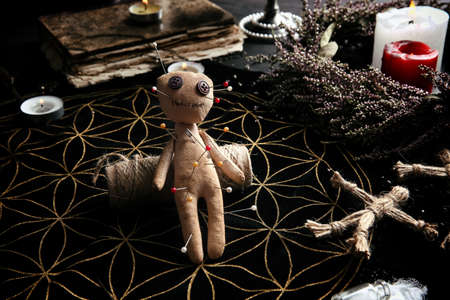 Voodoo doll pierced with pins on table. Curse ceremony