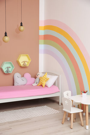 Cute child's room interior with beautiful rainbow painted on wallの写真素材