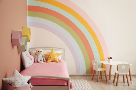 Cute child's room interior with beautiful rainbow painted on wallの写真素材