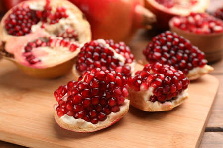 Delicious ripe pomegranates on wooden board, closeupの写真素材